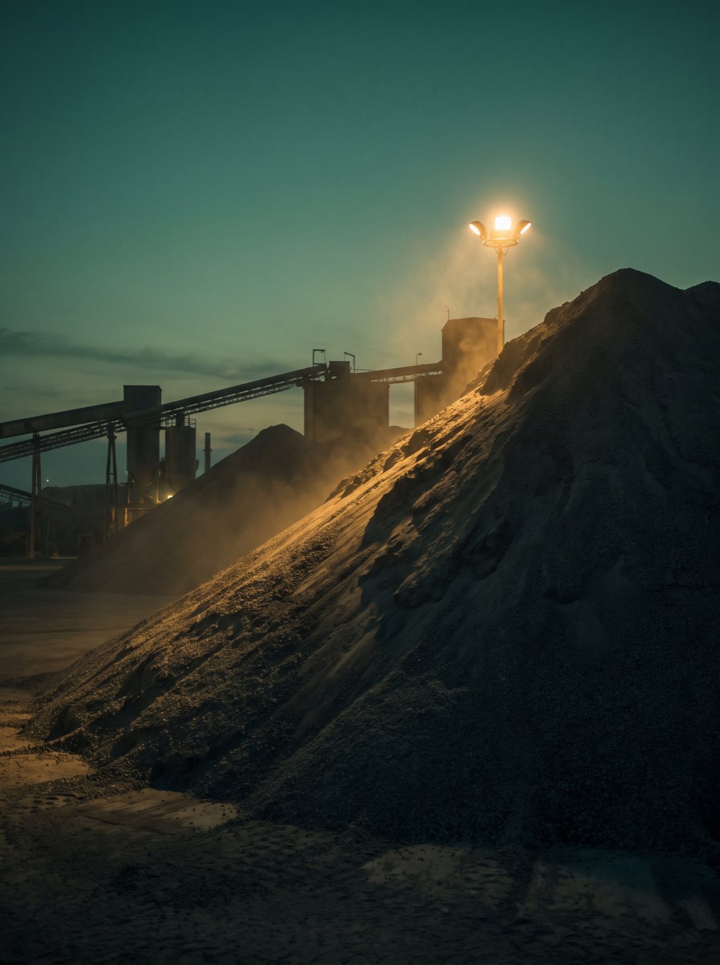 Stockpile of cement clinker under dusk floodlight