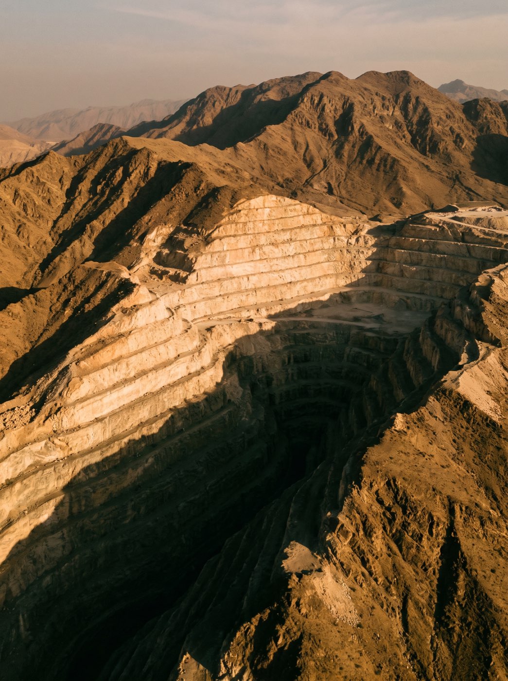 Terraced limestone quarry face in the Hajar mountains at first light